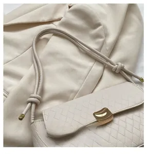 Detail of light beige woven leather bag with gold buckle and knotted shoulder strap