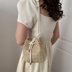Minimalist woven straw bucket bag with white drawstring for summer beach and vacation