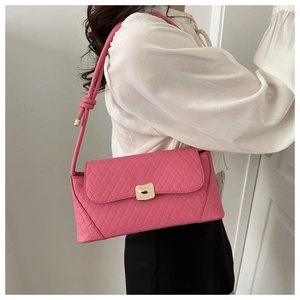Side view of a pink quilted shoulder bag with golden clasp worn by a model