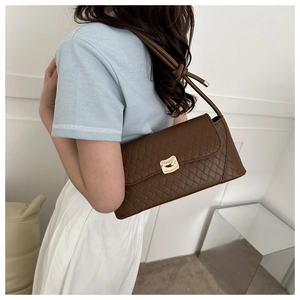 Brown quilted shoulder bag with gold clasp shown on model back for size reference