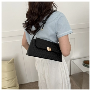 Detail of black quilted shoulder bag featuring gold hardware and elegant knot strap