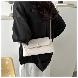 Rear view of a model wearing a white quilted rectangular crossbody bag with gold buckle