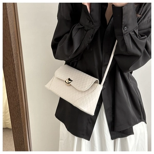 Detailed view of cream quilted shoulder bag featuring an elegant gold crescent metal clasp