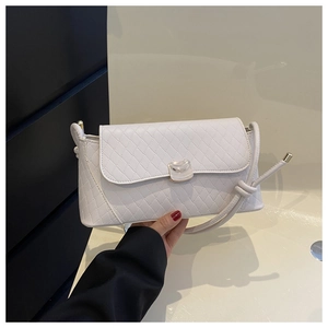 Detail view of white quilted crossbody bag featuring a unique knot shoulder strap and lock