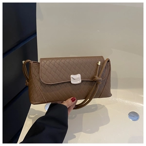 Close-up of brown woven leather texture and silver buckle on a stylish baguette bag