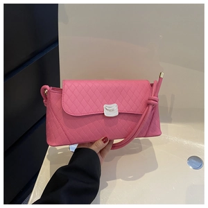 Close-up of pink quilted baguette bag with silver buckle and knotted shoulder strap