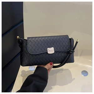 Close-up of black quilted shoulder bag with silver curved metal buckle and thin straps