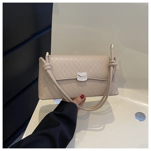 Detailed close-up of a beige quilted crossbody bag with silver hardware clasp and straps
