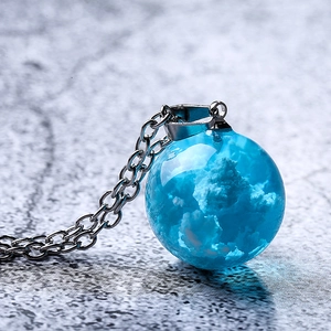 Blue sky and white cloud glass ball pendant necklace with silver chain on stone surface