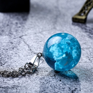 Macro detail of sky blue cloud glass ball pendant on a delicate silver chain