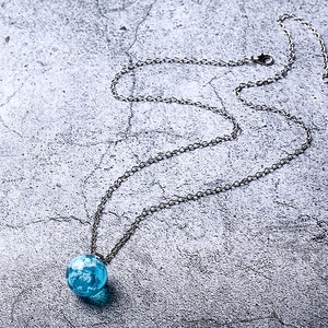 Detailed view of spherical glass pendant featuring blue sky and white clouds on metal chain