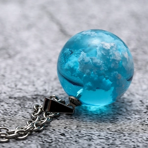 Macro shot of a blue spherical glass pendant featuring detailed white cloud patterns