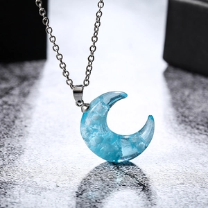 Macro shot of silver moon necklace featuring blue sky and white cloud resin pendant