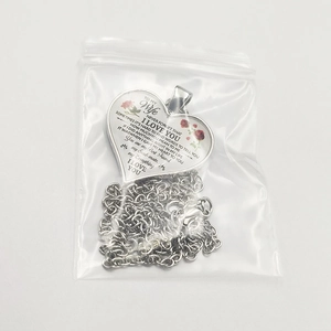Detail of heart pendant necklace for wife with red rose and emotional engraving in a bag