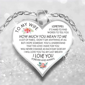 Macro detail of heart-shaped necklace with floral motifs and sentimental text for wife