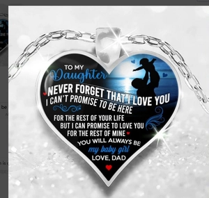 Macro detail of silver heart pendant with father and daughter silhouette and emotional text