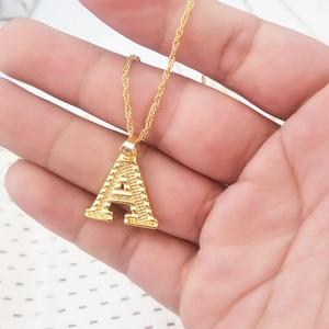 Nahaufnahme der 18K vergoldeten Buchstabe A Kette mit Rautenmuster auf einer Wellenkette