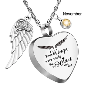 Detail van de zilveren hart urn ketting met engelenvleugel en gele november geboortesteen