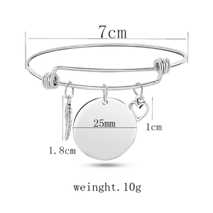 Silver adjustable bangle with round disc, hollow heart, and wing charms in a 7cm diameter