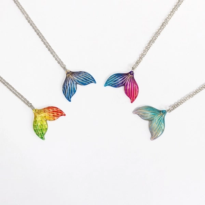 Detailed top view of four gradient acrylic mermaid tail necklaces in various colors