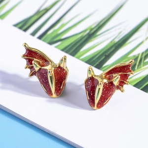 Close-up of golden dragon stud earrings with red enamel finish and silver glitter details