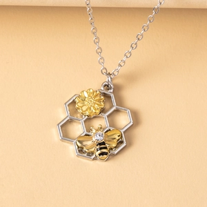 Detailed view of honeycomb pendant with golden bee and flower on a silver hexagon base