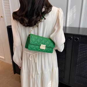 Elegant emerald green quilted crossbody bag with gold chain strap shown on a model