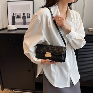 Chic black quilted crossbody bag with gold hardware shown on a shoulder in modern interior