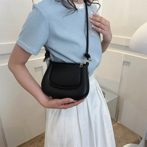 Elegant black leather saddle crossbody bag with gold hardware and slim shoulder strap