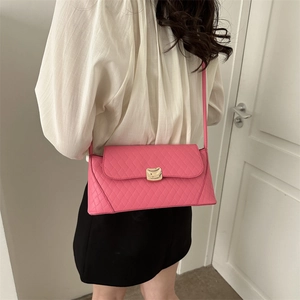 Pink quilted baguette shoulder bag with gold clasp shown on a white-clad model