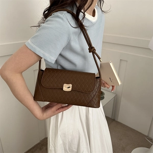 Quilted dark brown baguette bag with golden metal buckle and knotted strap on model