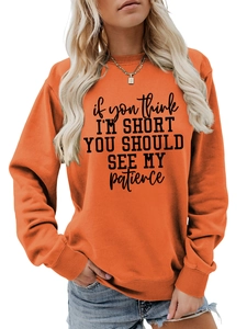 Detail of orange crewneck sweatshirt featuring black humor text print on soft fabric