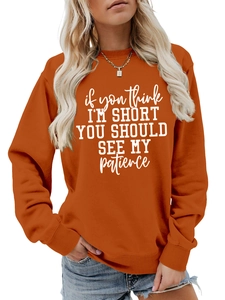 Detail view of the orange crewneck sweatshirt featuring white humor text typography