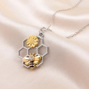 Exquisite gold bee and flower charm necklace on champagne satin background