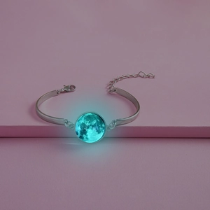 Gros plan du bracelet lune montrant un effet lumineux turquoise dans le noir