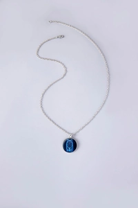 Dettaglio della collana a catena argento con pendente rotondo totem lupo blu