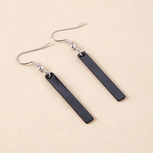 Minimalist black rectangular drop earrings with silver metal hooks on a beige background