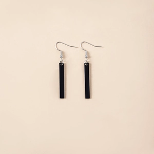 Close-up of sleek black rectangular pendant earrings with minimalist silver metal hooks
