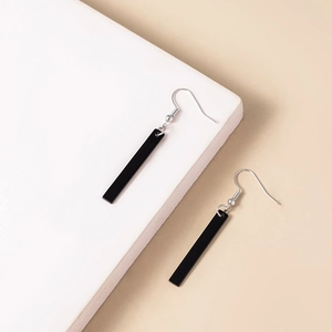 Detail of sleek black rectangular dangle earrings with silver hooks on geometric display