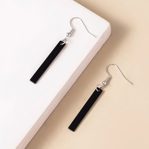 Macro detail of minimalist long black rectangular pendant earrings with silver hooks