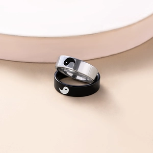 Paire de bagues de couple Yin Yang en acier inoxydable sur un support beige épuré
