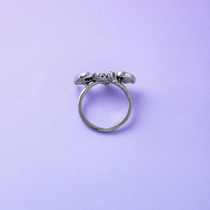 Vintage Gothic silver devil wing ring with pink heart gemstone on purple background