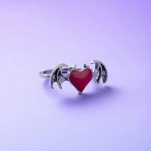 Macro shot of gothic demon wing ring featuring a polished red heart and vintage silver finish