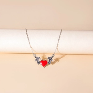 Detailed view of gothic red heart pendant with silver bat wings on white display