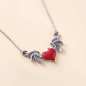 Gothic punk devil wing necklace with red heart pendant on a minimalist cream background
