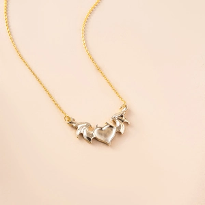 Detailed view of the warm gold heart pendant with intricate devil wings and cross chain