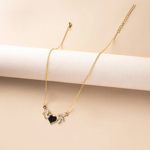 Detail of gothic devil wing necklace with black heart pendant on a display stand