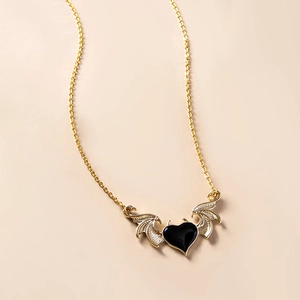 Macro view of gothic devil wing heart pendant with black enamel finish and gold texture