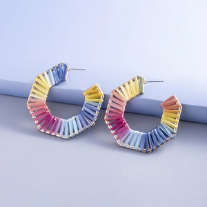 Detail van handgemaakte regenboog raffia hexagon oorbellen met gouden metalen frame