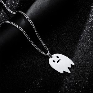 Macro shot of silver ghost pendant with hollow eyes on sparkling black starry background